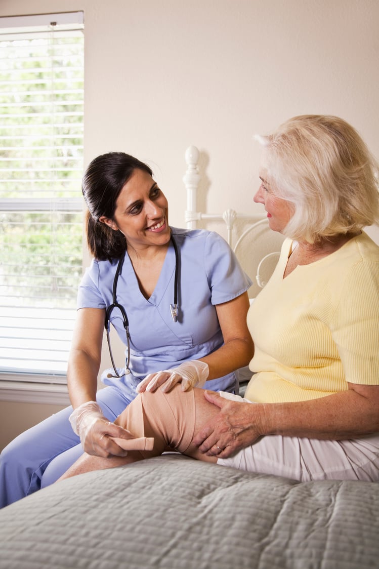 Healthcare worker bandaging patient's knee